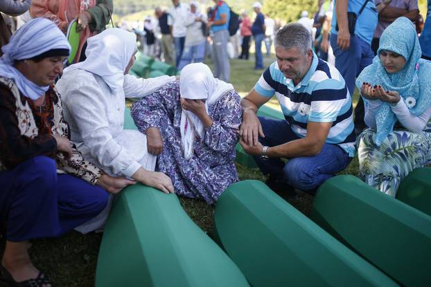 People mourn near coffins of their relatives, who are newly identified victims of the 1995 Srebrenica massacre, which are lined up for a joint burial in Potocari near Srebrenica