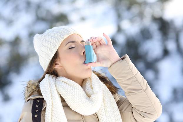 Woman using asthma inhaler in a cold winter