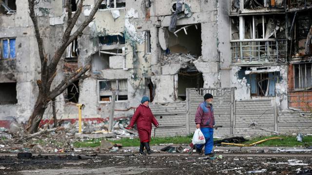 FILE PHOTO: People walk near a destroyed residential building in Mariupol