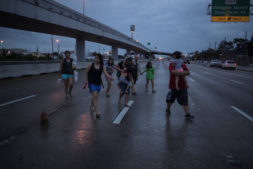 The Duong family, with children, parents and dog in tow, walks along Interstate 45 while escaping flood waters from Tropical Storm Harvey in Houston