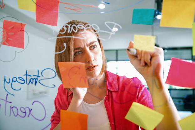 Young beautiful business leader writing marketing idea on board. Immaculate.