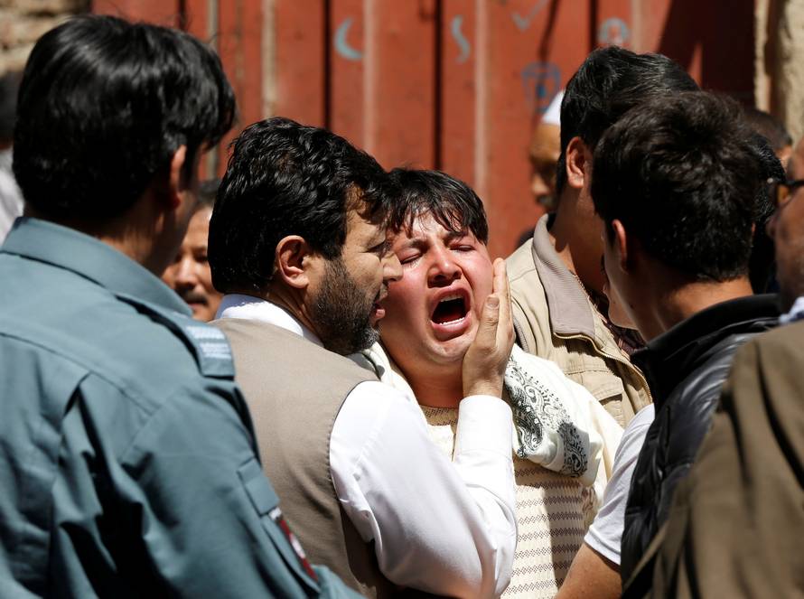 A man reacts as others comfort him at the site of a suicide attack in Kabul