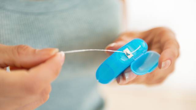 closeup on young woman with dental floss