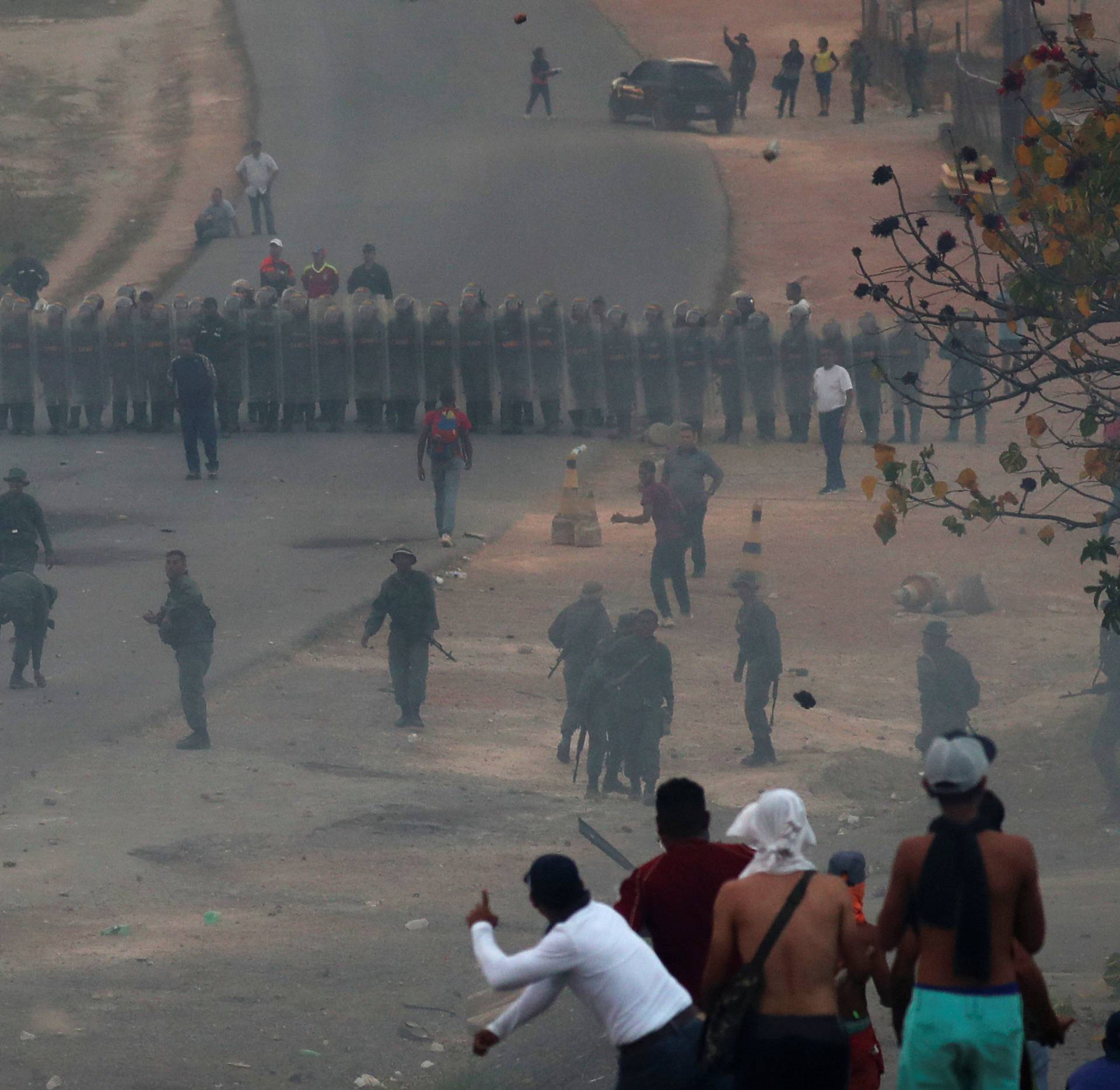 People look on during clashes with Venezuelan soldiers along the border between Venezuela and Brazil in Pacaraima