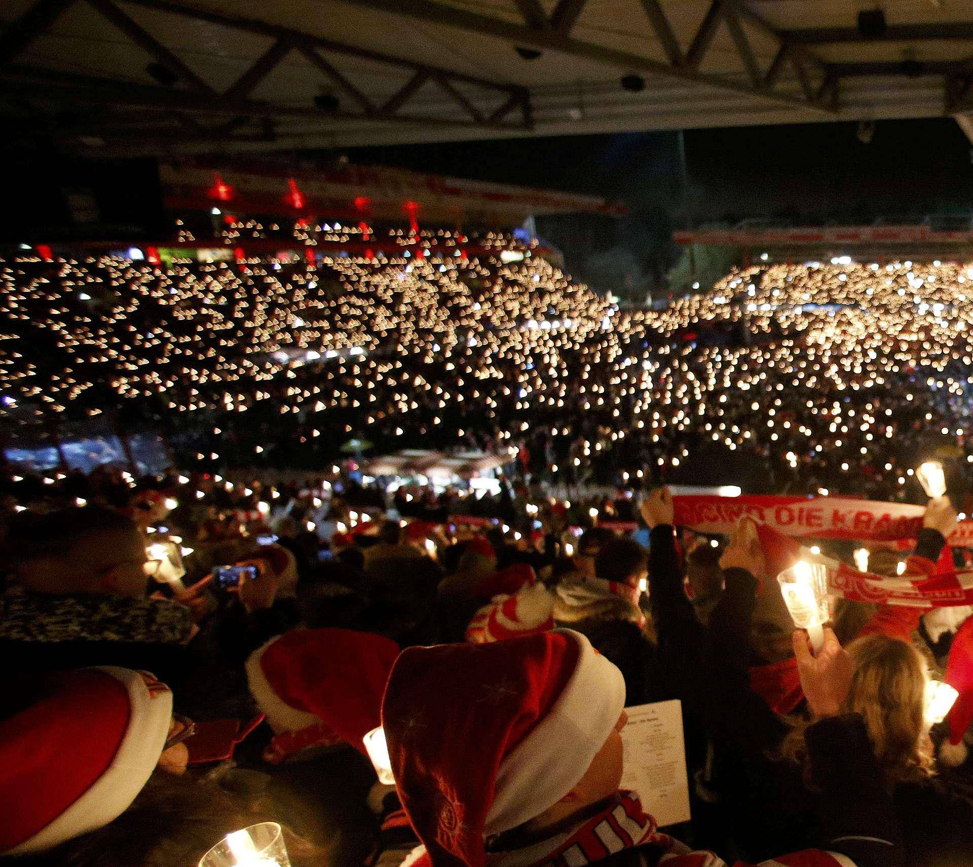 People attend the "Weihnachtssingen", a candle-lit carol concert at the Alte Foersterei stadium in Berlin