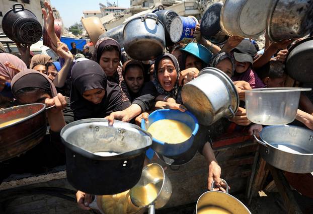 Palestinians wait to receive food from a charity kitchen, in Gaza City