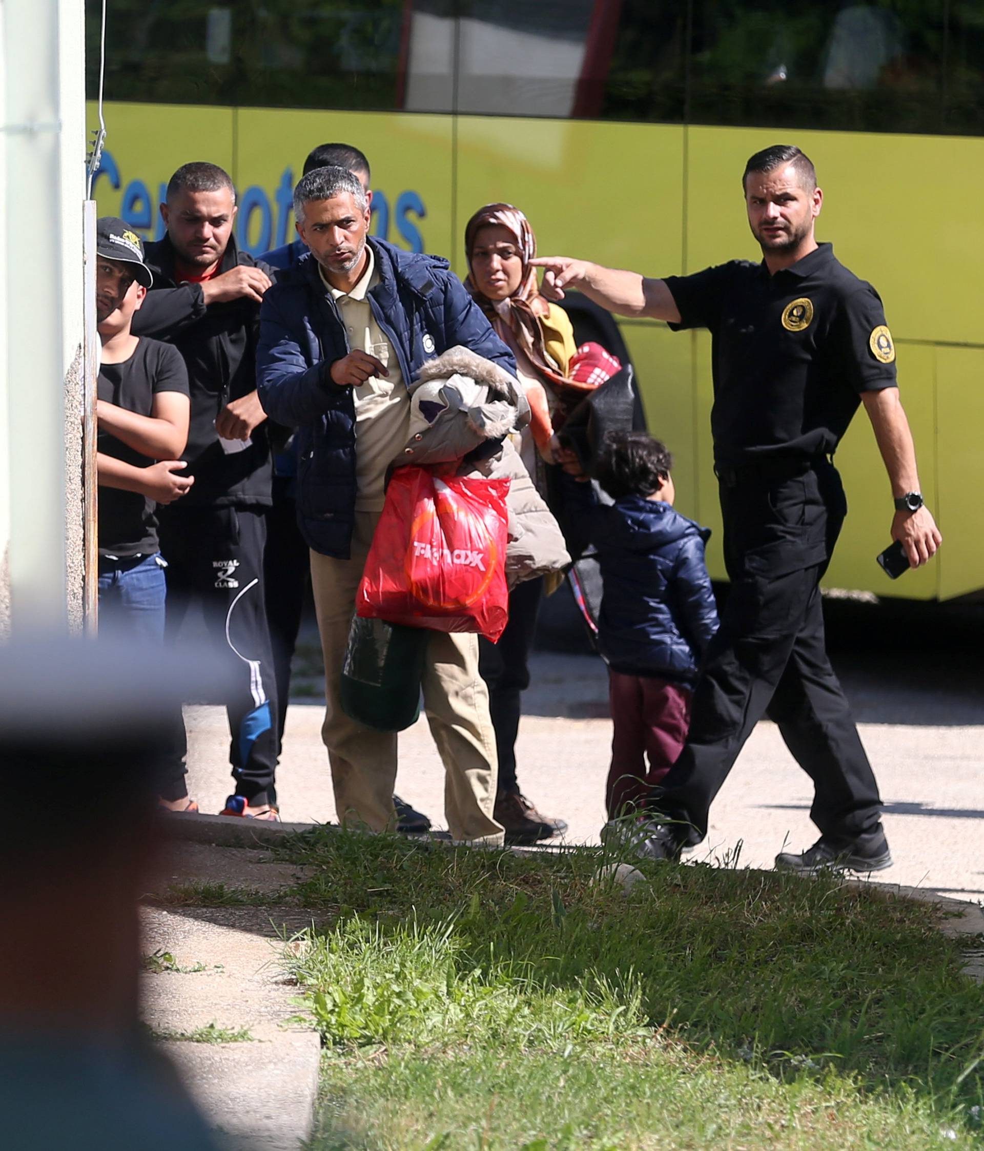 Migrants leave a bus at a camp in Salakovac