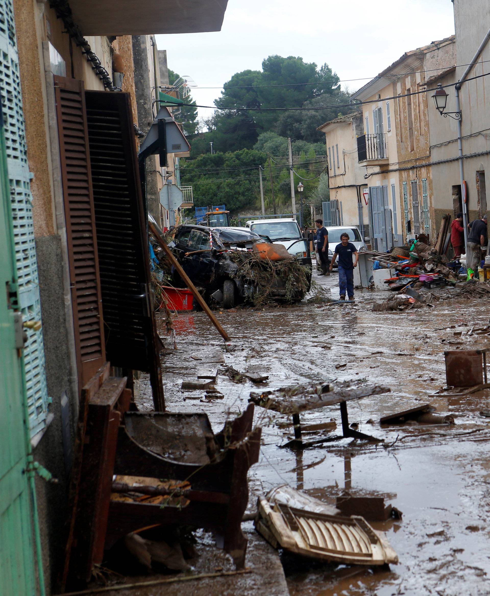 People walk on the debris-ridden streets as heavy rain and flash floods hit Sant Llorenc de Cardassar on the island of Mallorca