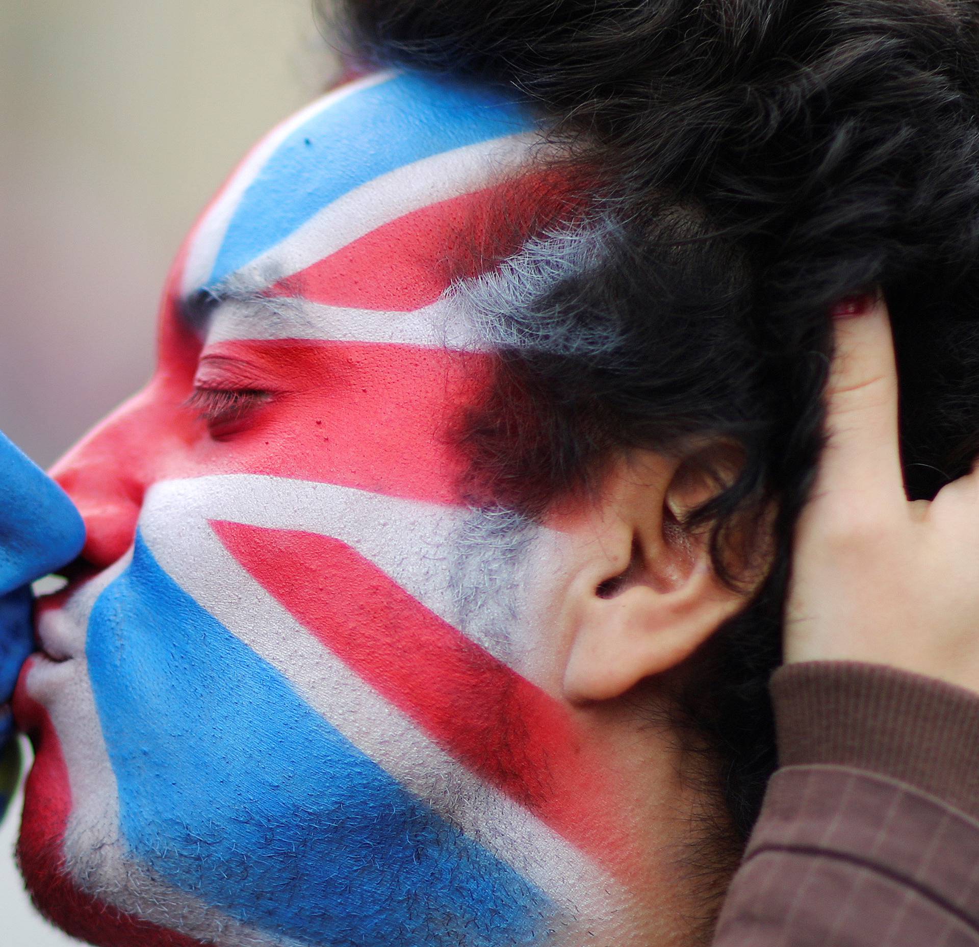 Two activists with the EU flag and Union Jack painted on their faces kiss each other in front of Brandenburg Gate to protest against Brexit in Berlin