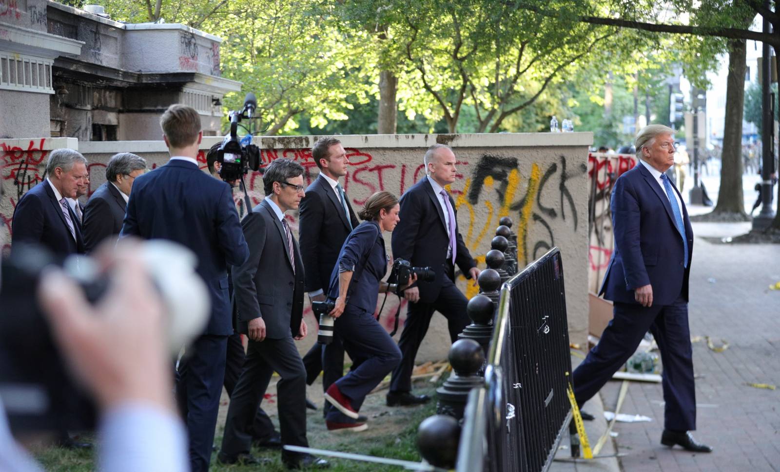 U.S. President Trump walks past a building defaced with graffiti by protestors in Washington