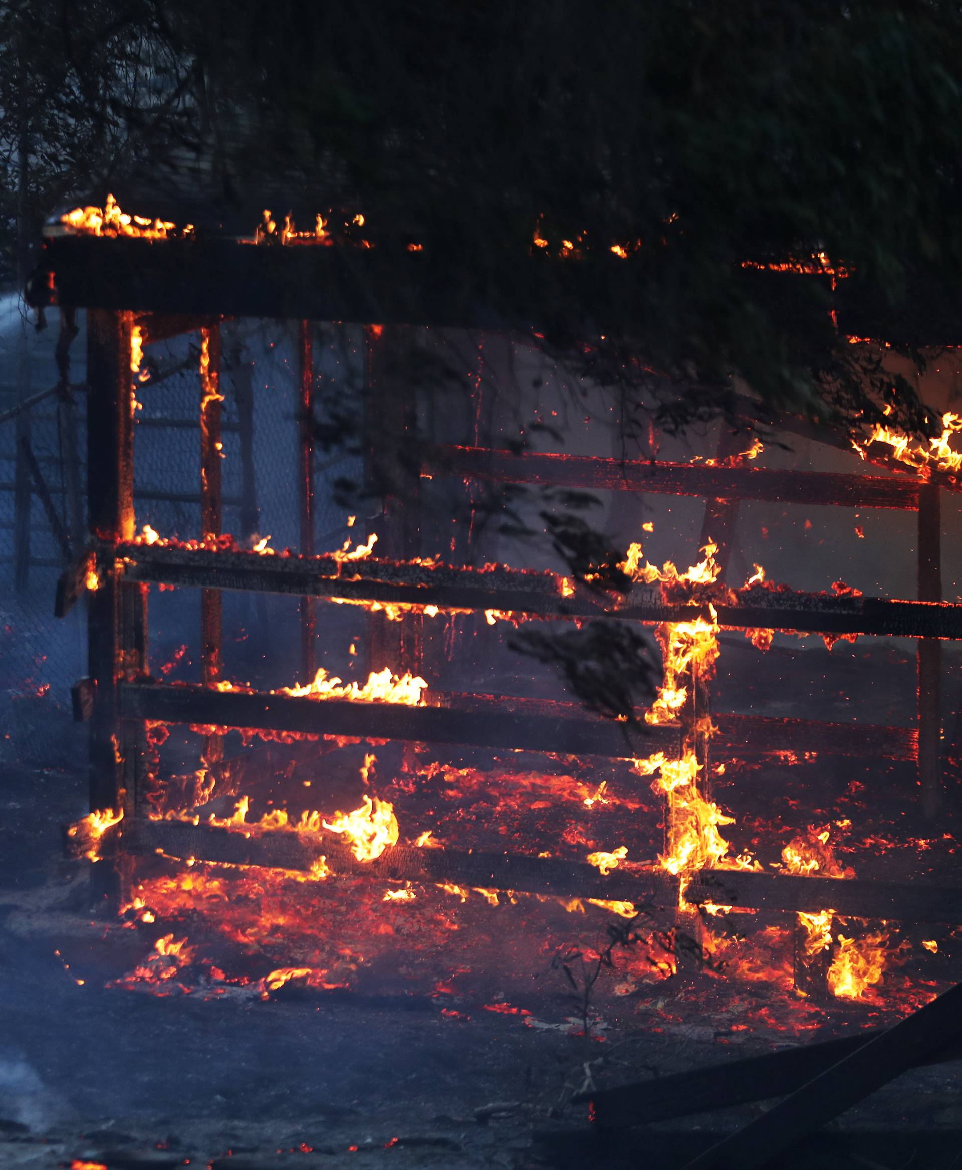 A firefighter sprays water on the Lilac Fire a fast moving wildfire in Bonsall