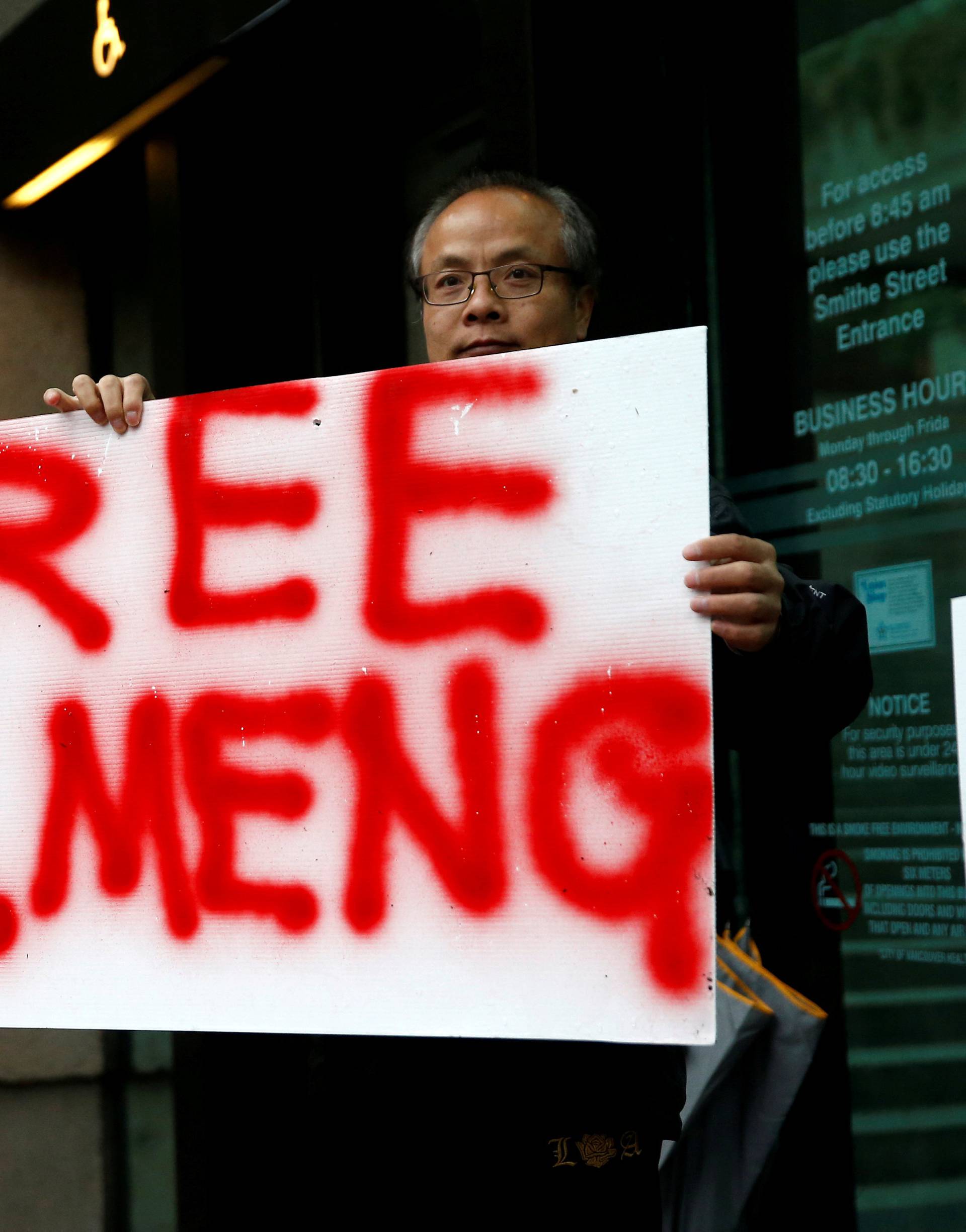 FILE PHOTO: Long holds a sign outside the B.C. Supreme Court bail hearing of Huawei CFO Meng Wanzhou