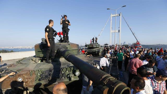 Policemen stand on a military vehicle after troops involved in the coup surrendered on the Bosphorus Bridge in Istanbul