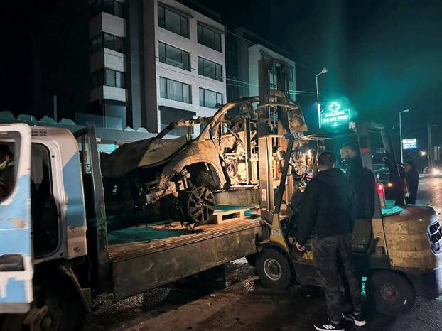 A truck carries a burned-out car that was hit by an Israeli airstrike in Beirut