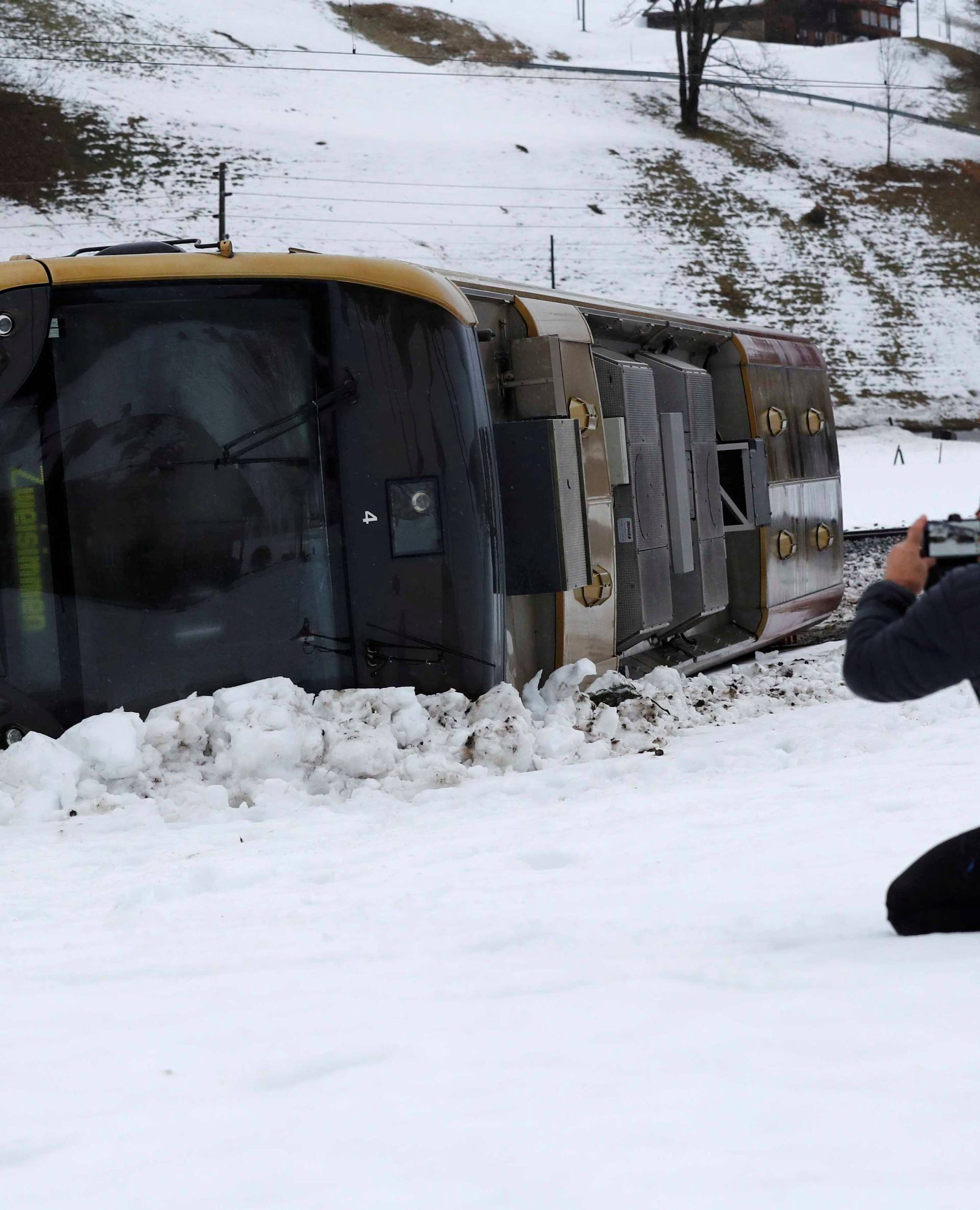 A man takes pictures of a carriage of the MOB train lying on its side after if was pushed out of the tracks by gusts of wind during storm Eleanor near Lenk