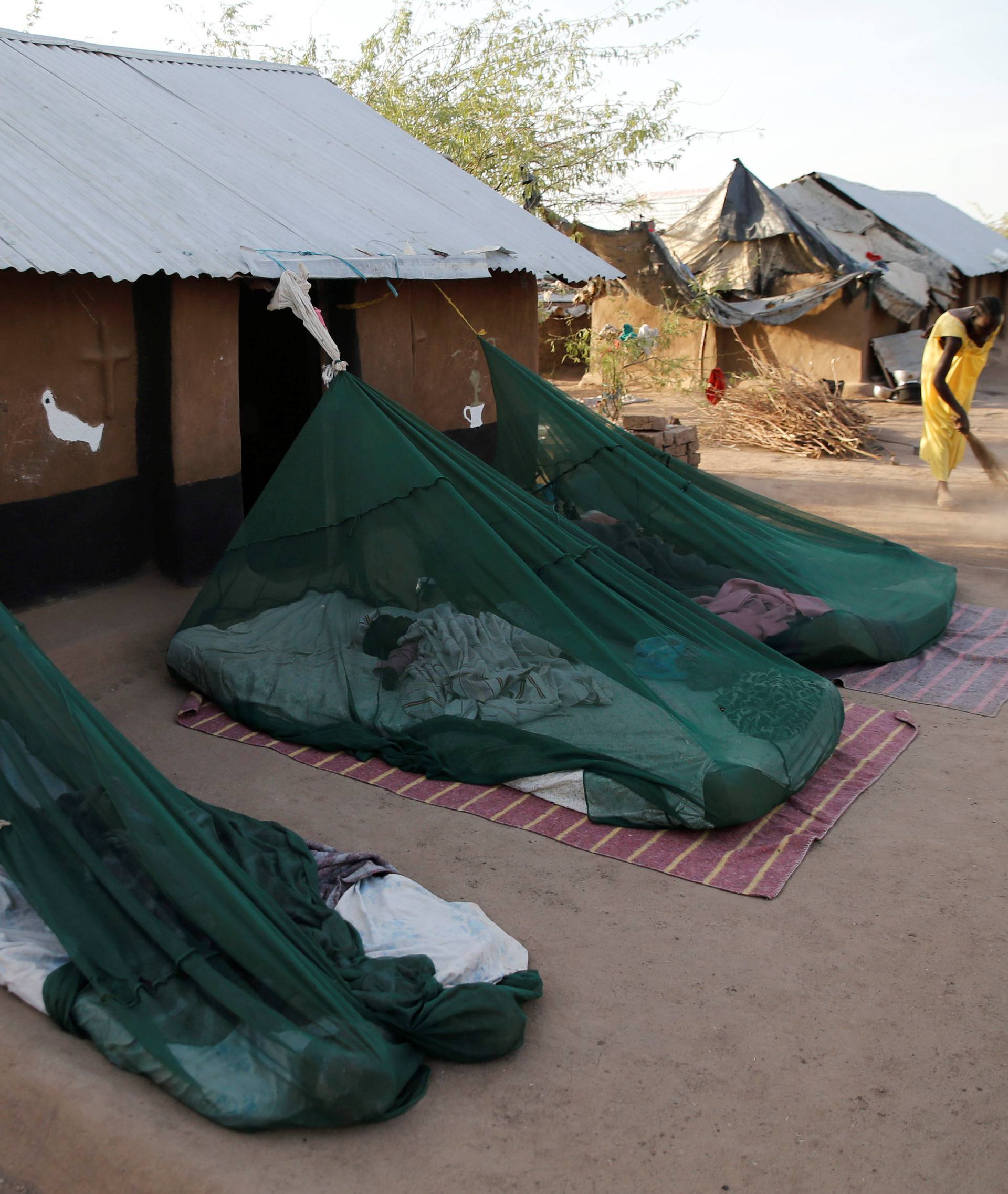 A South Sudanese refugee woman sweeps as her children sleep inside insecticide-treated bednets outside their house within Kalobeyei Settlement outside the Kakuma refugee camp in Turkana county