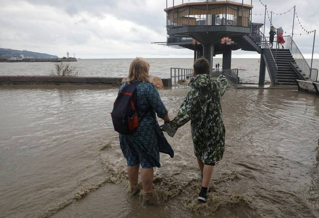 People gather on a flooded embankment after heavy rainfall in Yalta