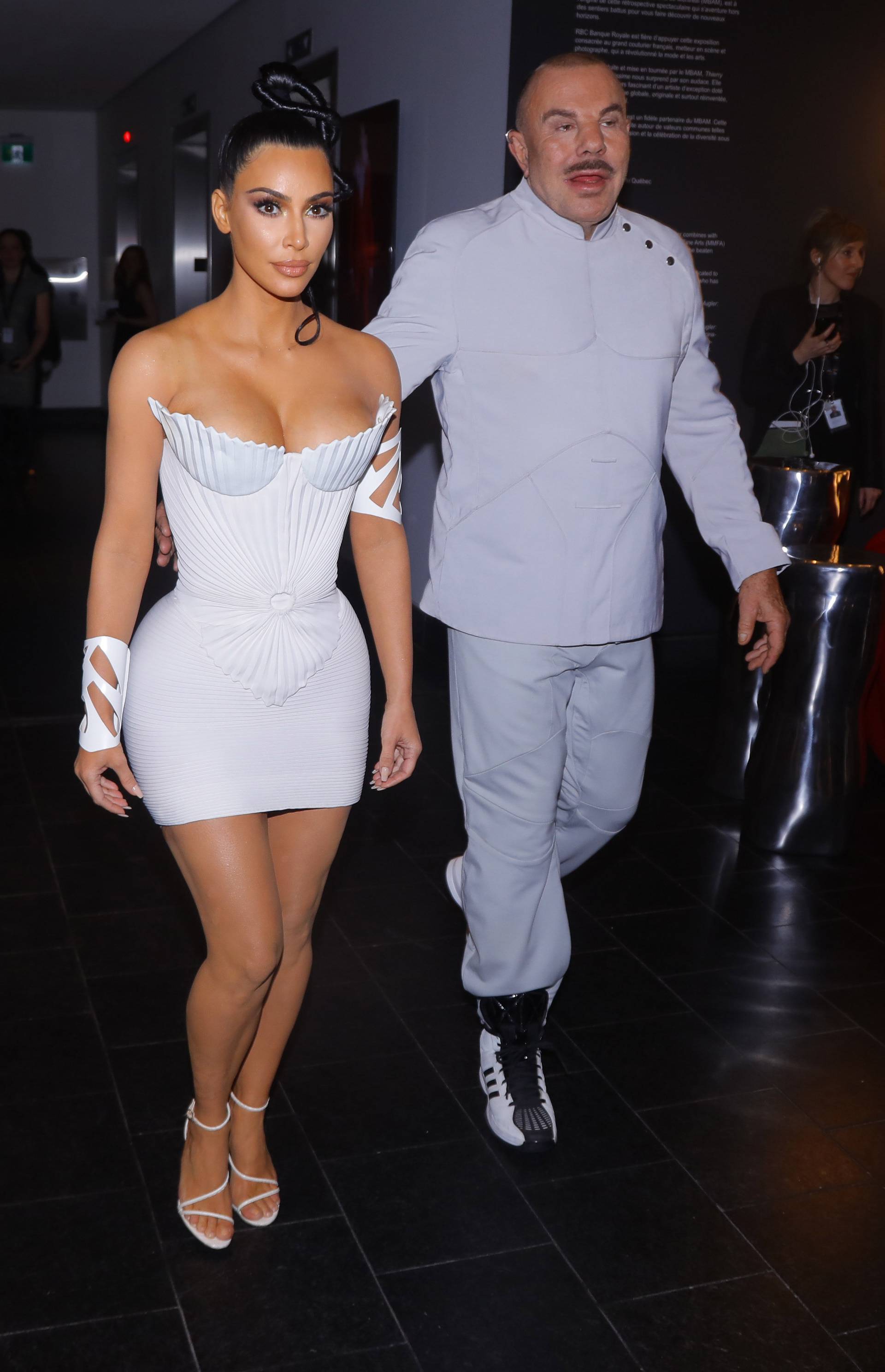 Kim Kardashian shows off her figure in a stylish all white dress and stuns while looking inside at the Thierry Mugler exhibition opening night in Montreal Canada