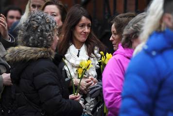 Schoolfriends bring yellow flowers to represent sunshine as they queue up to view Cranberries singer Dolores O'Riordan's coffin  as it is carried into St. Joseph's Church for a public reposal in Limerick