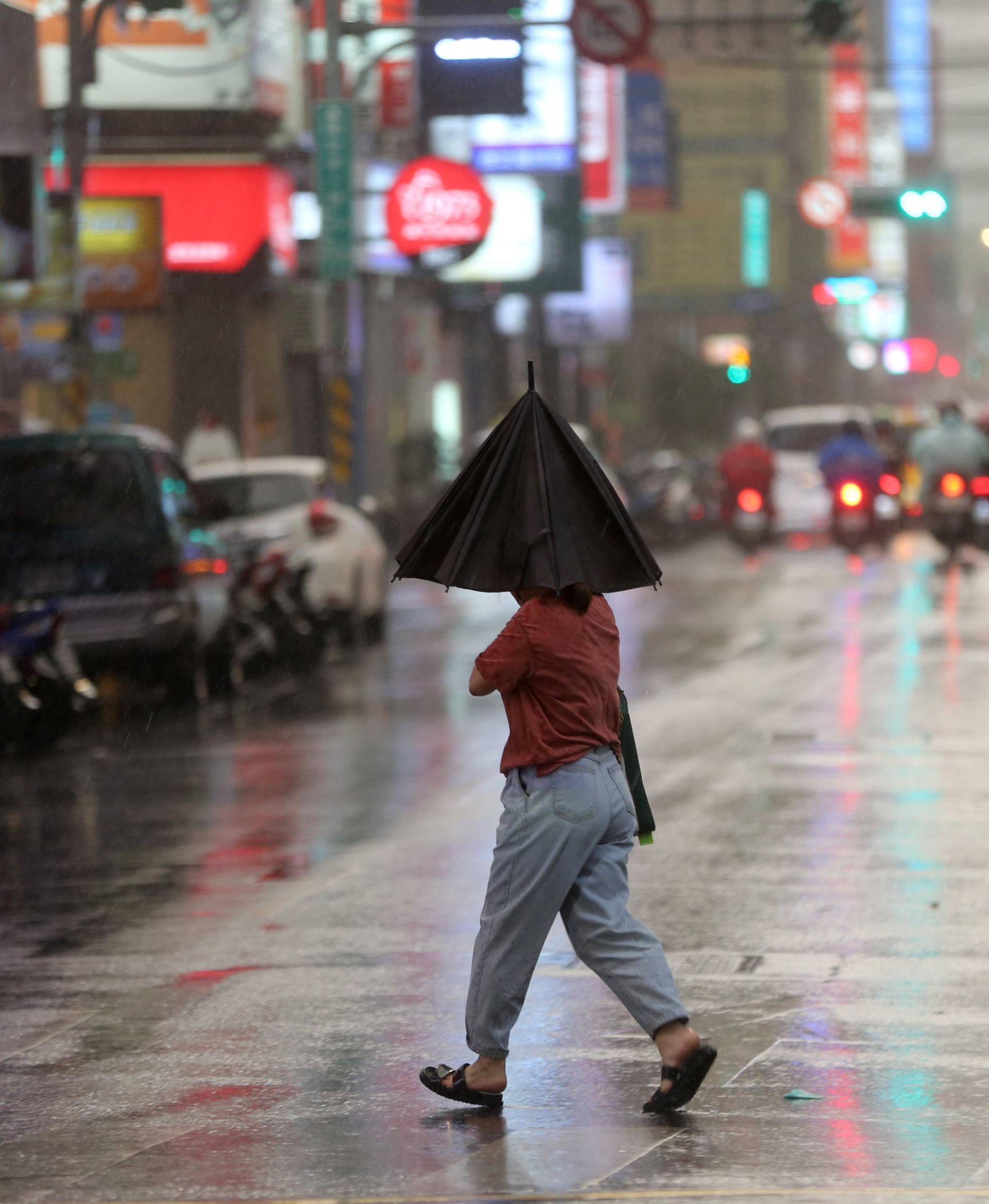 Person braves strong winds while crossing a street in Taipei
