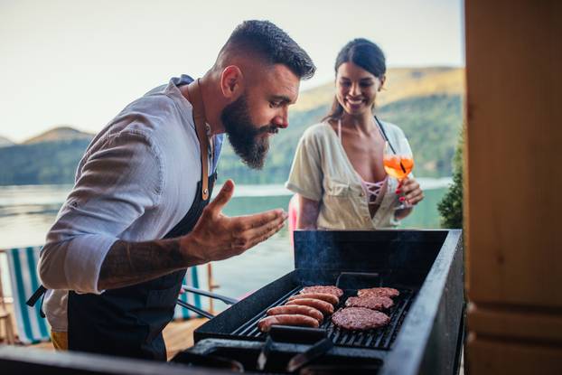 Male,Is,Barbecuing,Next,To,The,River,While,His,Girlfriend