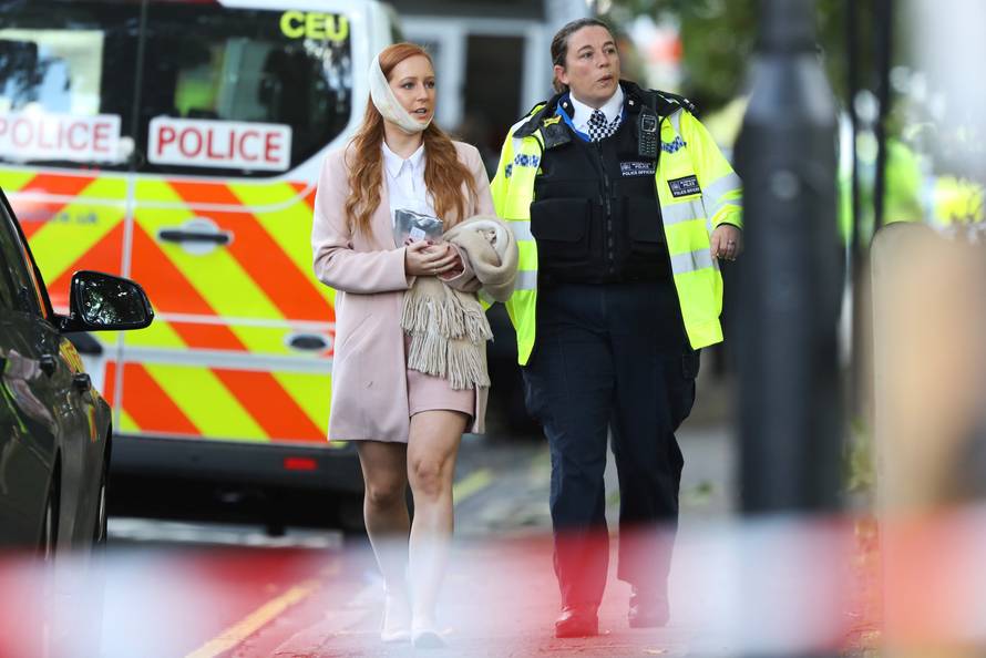 An injured woman is led away after an incident at Parsons Green underground station in London