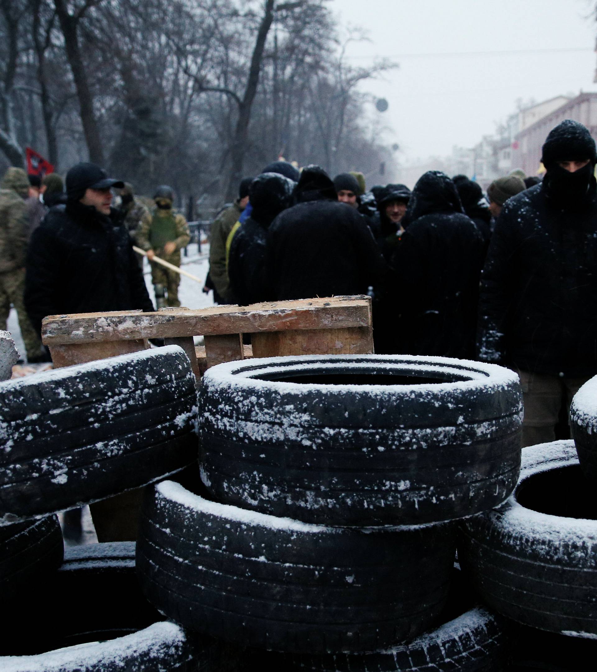 Anti-government protesters stand behind a barricade next to the Parliament building in Kiev