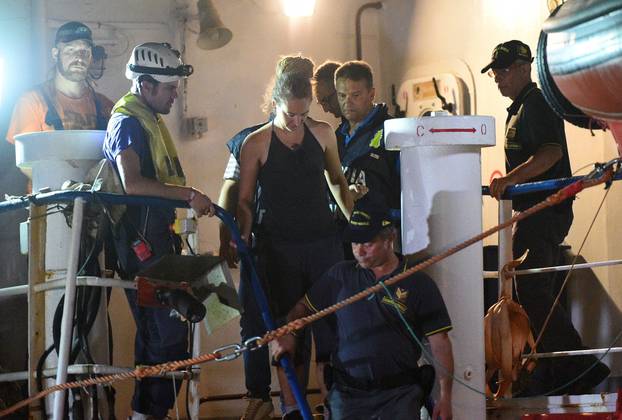 Carola Rackete, the 31-year-old Sea-Watch 3 captain, is escorted off the ship by police and taken away for questioning, in Lampedusa