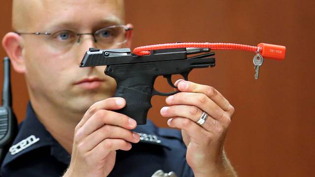 Sanford police officer Timothy Smith holds up the gun that was used to  kill Trayvon Martin, while testifying during George Zimmerman's murder trial in Seminole circuit court in Sanford