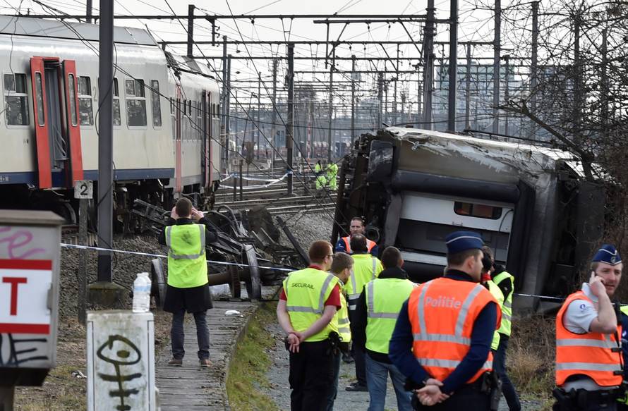 Rescuers and police officers stand next to the wreckage of a passenger train after it derailed in Kessel-Lo near Leuven