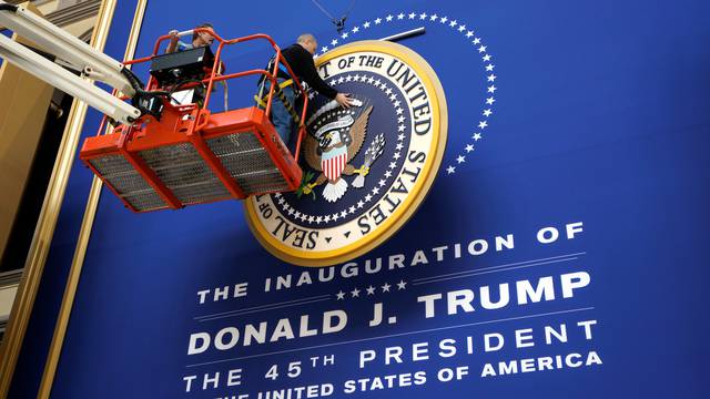 Workers install the presidential seal at the site of the Commander in Chief inaugural ball for President-elect Donald Trump in Washington, DC