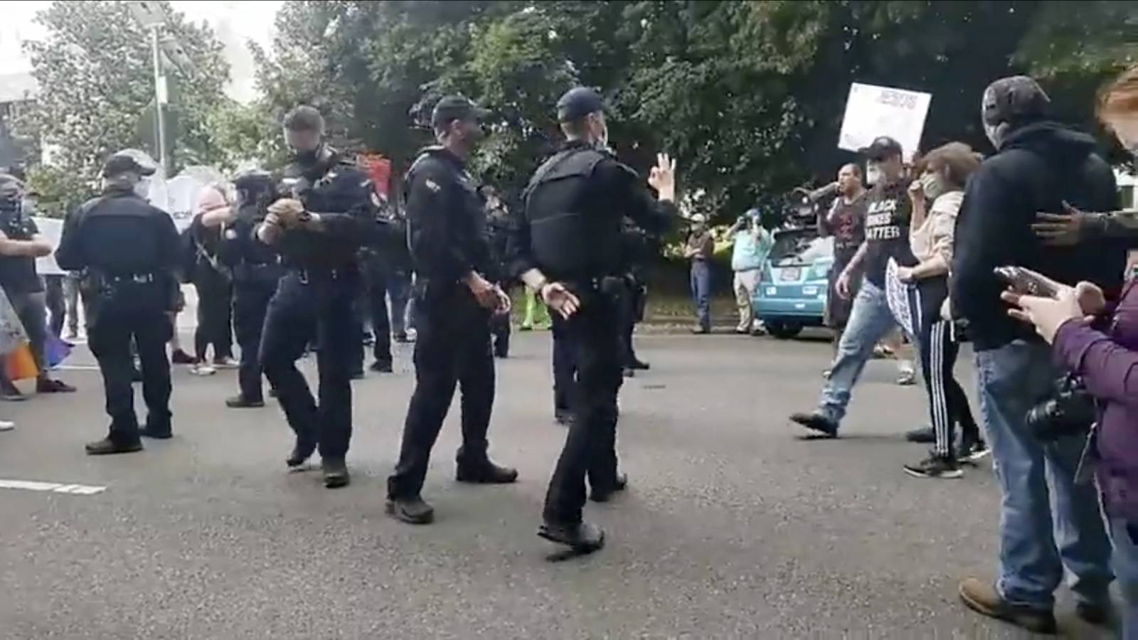 A state trooper appears to make a hand gesture with white supremacist associations during a Black Lives Matter rally in Salem