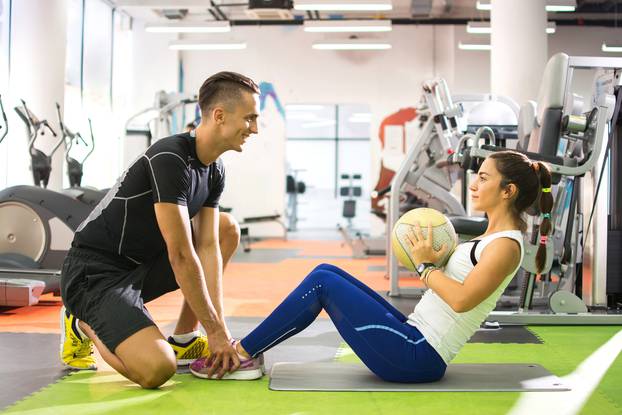 Female,Client,Doing,Abdominal,Crunches,With,Ball,While,Her,Personal