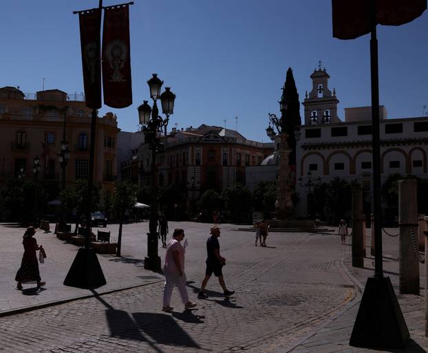 People walk in downtown Seville during a heatwave