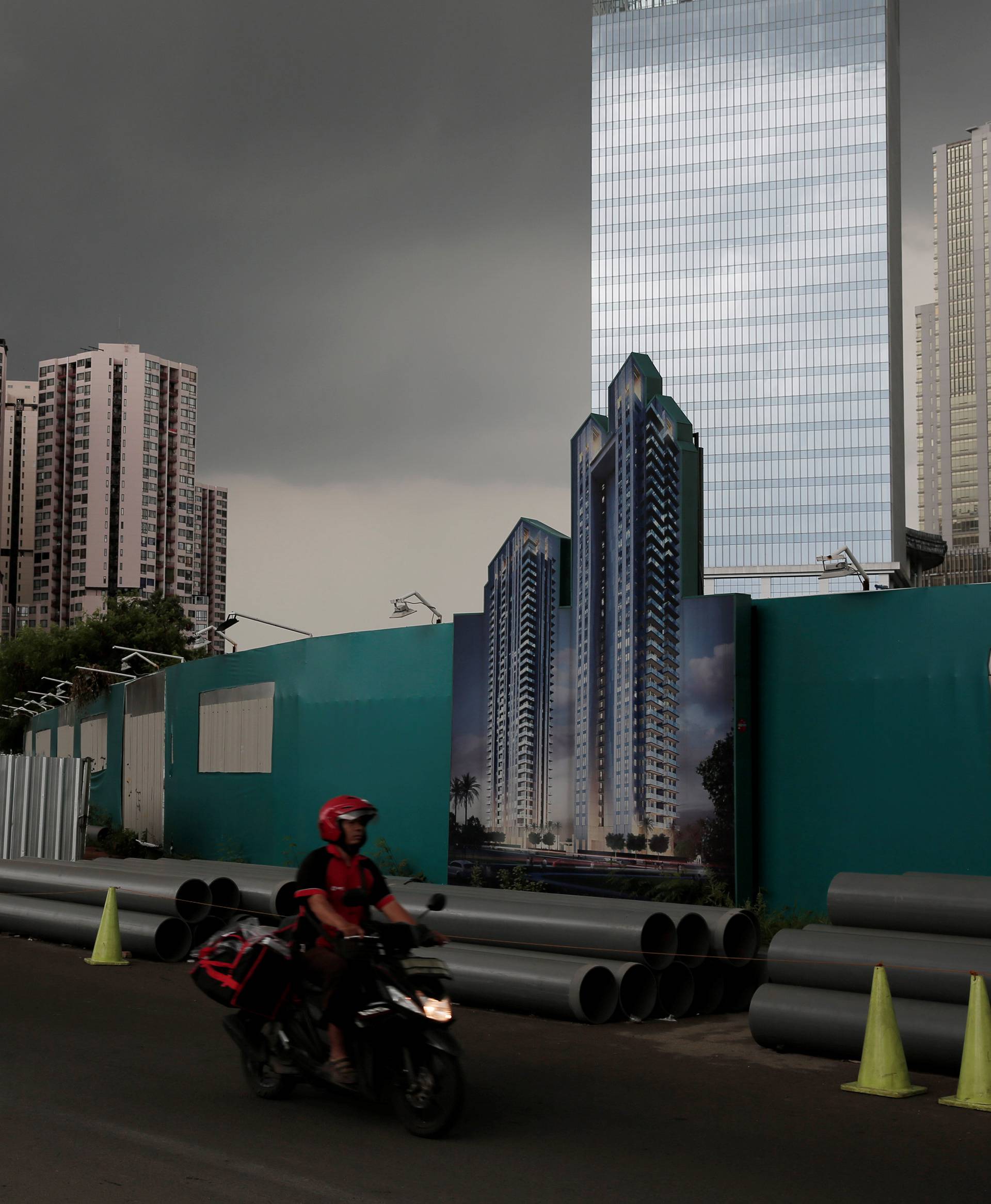 A man rides a motorcycle in front of an apartment advertisement at Kuningan apartment compound in Jakarta