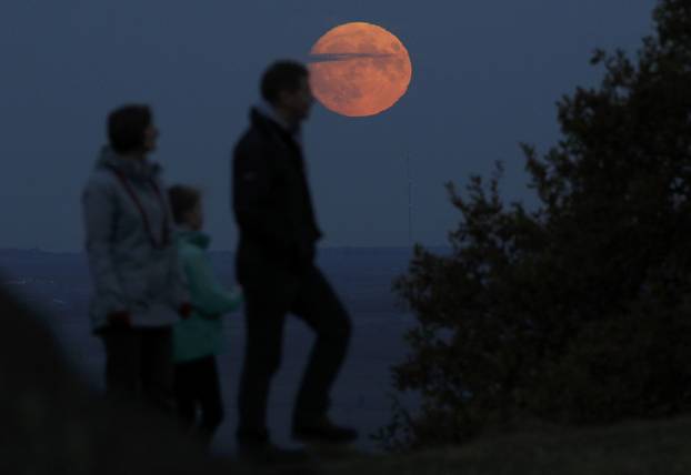 A family watch the moon rise a day before the "supermoon" spectacle on Beacon Hill near Loughborough