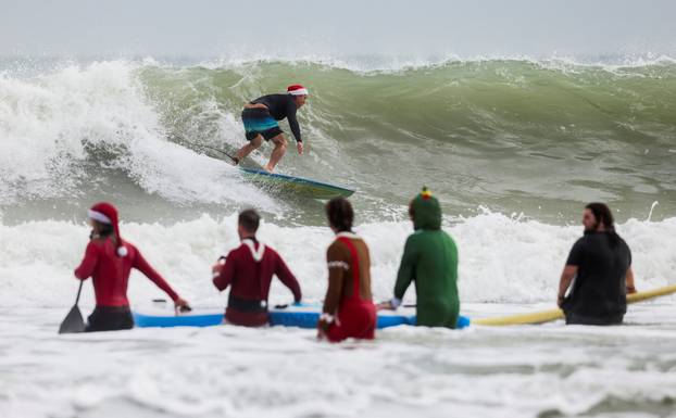 Surfing Santas take to the waves at the annual Christmas Eve event in Cocoa Beach