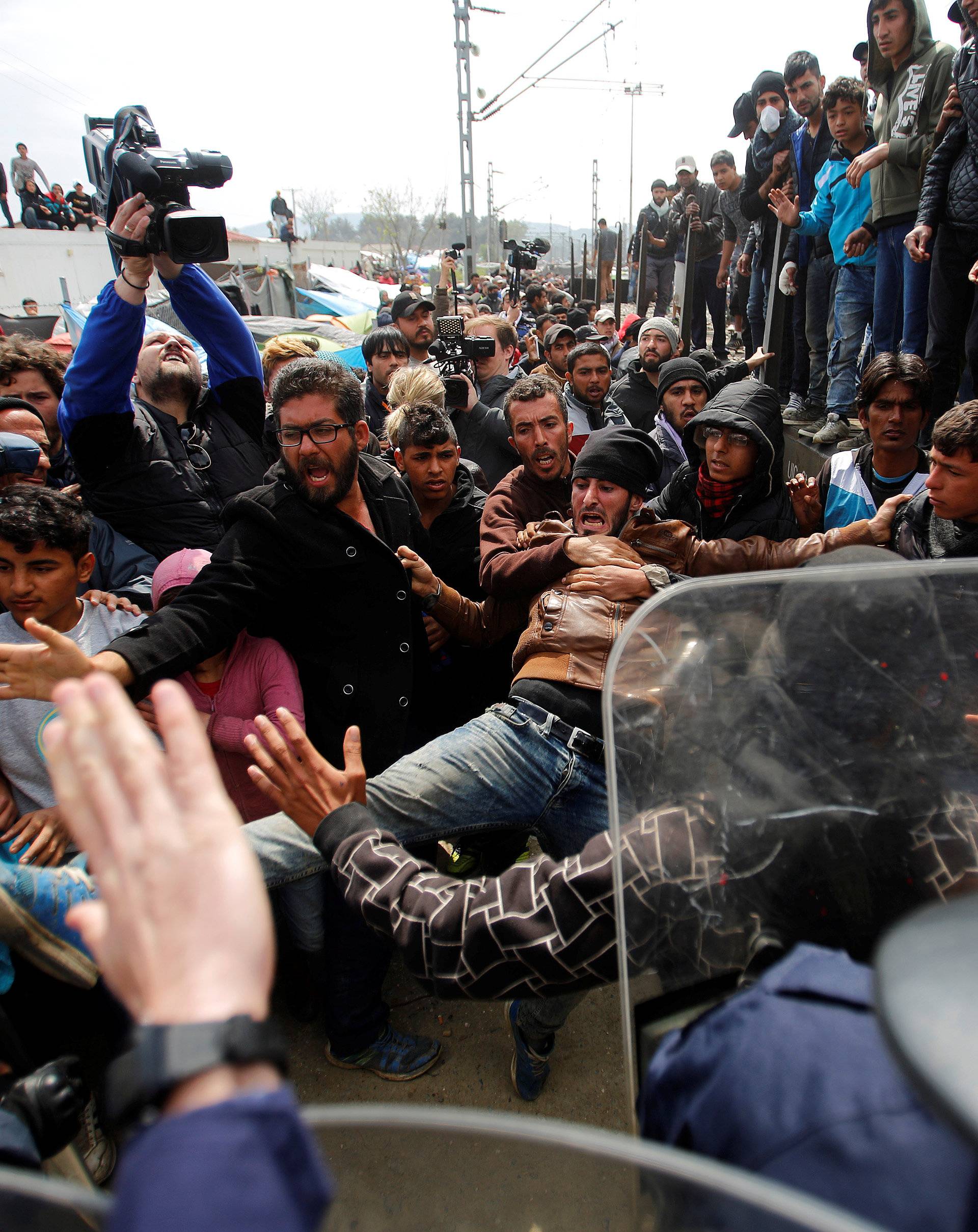 Migrants and refugees scuffle with Greek police after they tried to push a train carriage through a police bus on rail tracks leading to Macedonia at a makeshift camp at the Greek-Macedonian border near the village of Idomeni