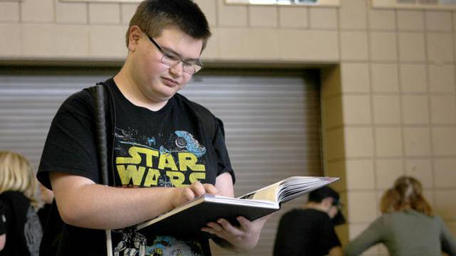 RJ Sampson reads his yearbook in the entryway of Conifer High Sc