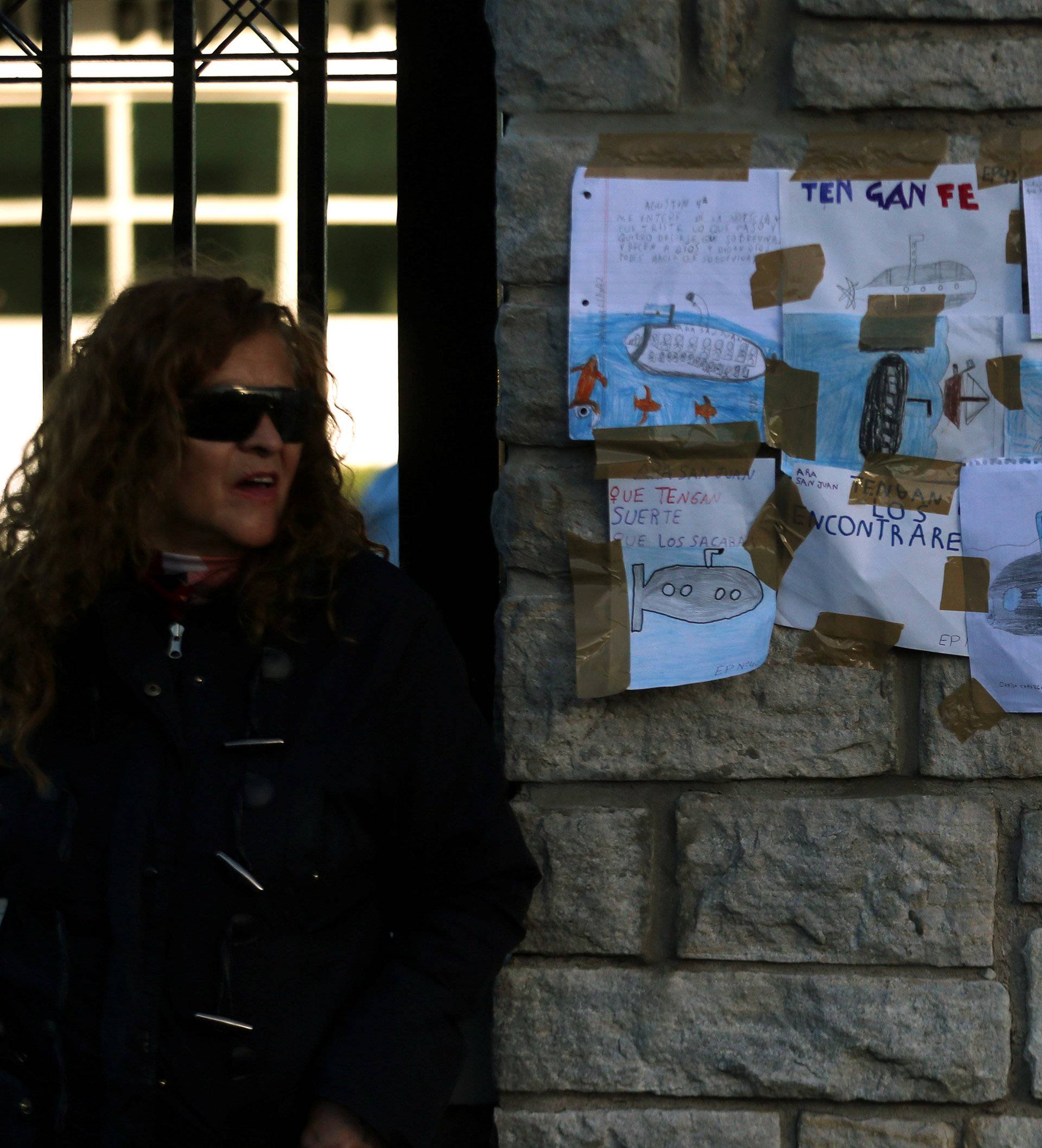 A woman stands next to drawings with messages in support of the 44 crew members of the missing at sea ARA San Juan submarine placed on a wall at the entrance of an Argentine naval base in Mar del Plata