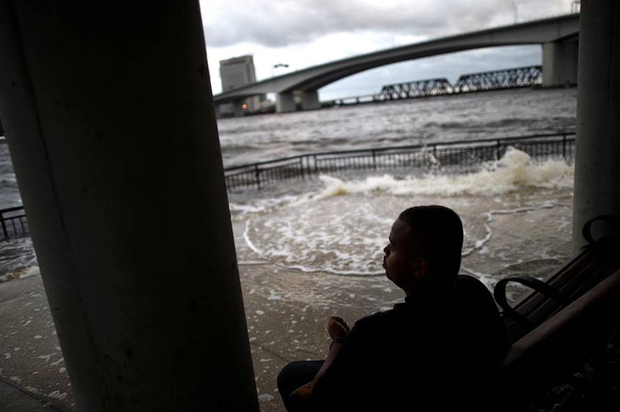 Lui Nesbitt, 22, sits on a bench beside floodwaters after Hurricane Irma in Jacksonville