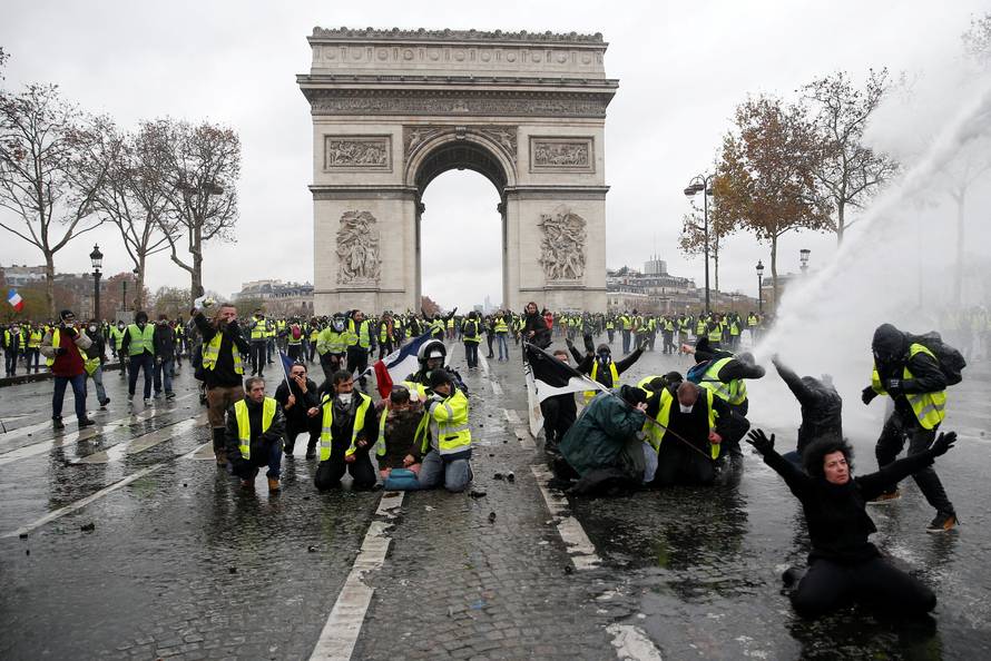 Protesters wearing yellow vests, a symbol of a French drivers' protest against higher diesel taxes, face off with French riot police during clashes at the Place de l'Etoile near the Arc de Triomphe in Paris