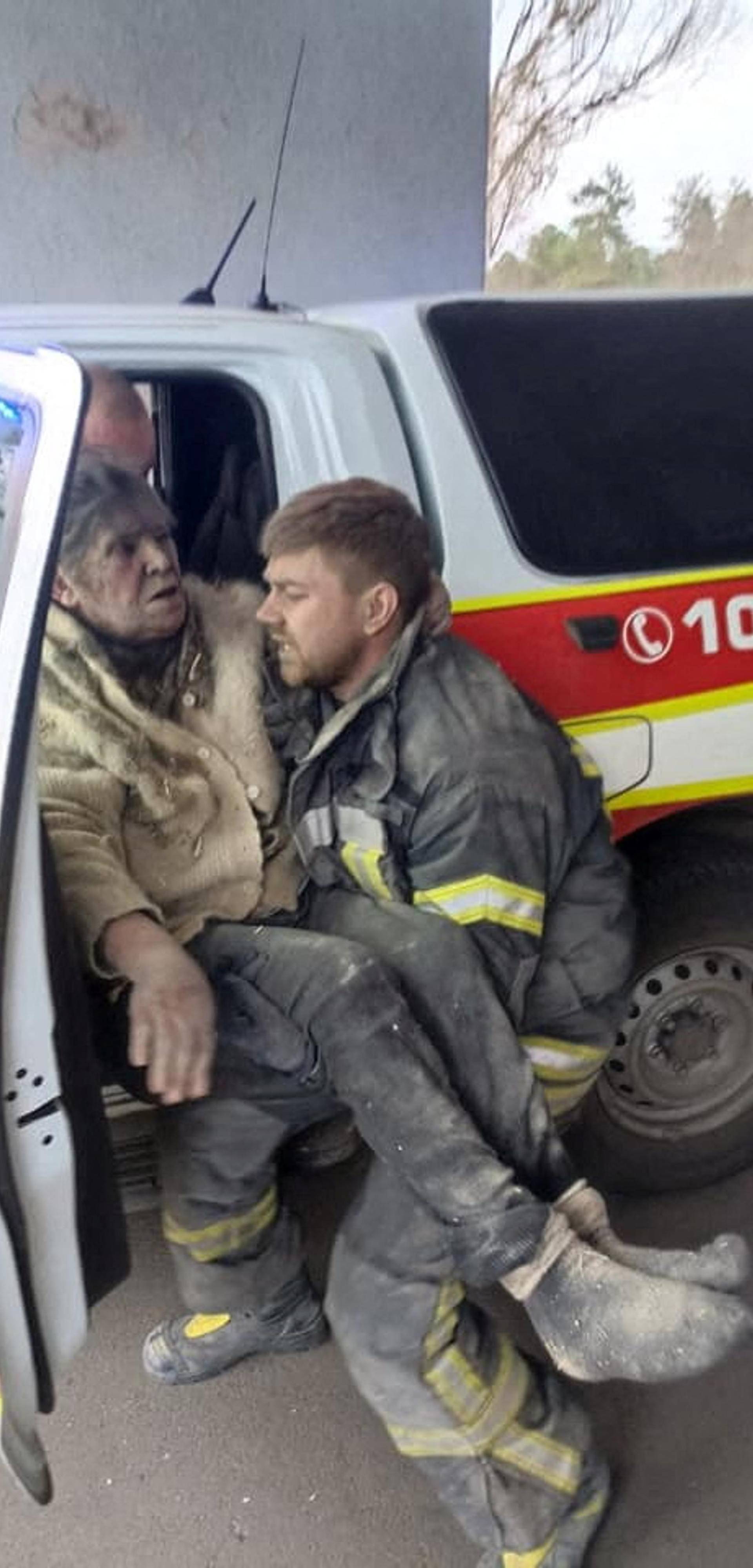 A rescuer carries a woman who was removed from debris after a military strike in Rubizhne