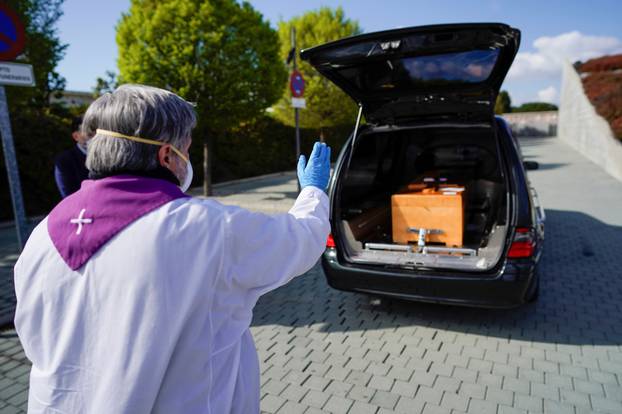 A priest gives a response in front the coffin of a woman who died of coronavirus disease (COVID-19), during partial lockdown to combat the coronavirus disease (COVID-19) outbreak in Madrid
