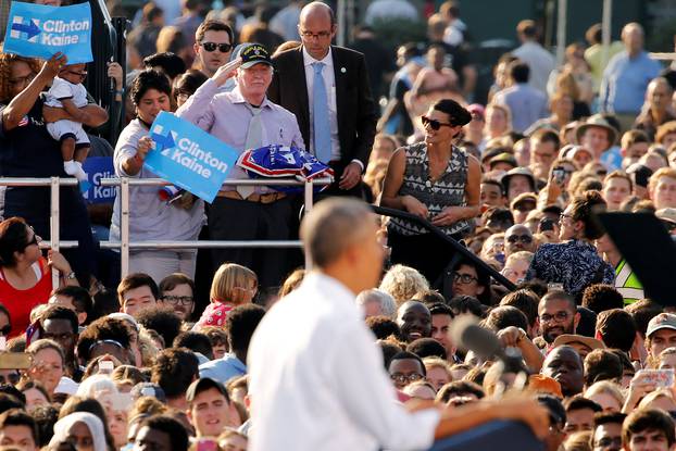 A man with a Trump campaign sign salutes before he is removed from U.S. President Barack Obama