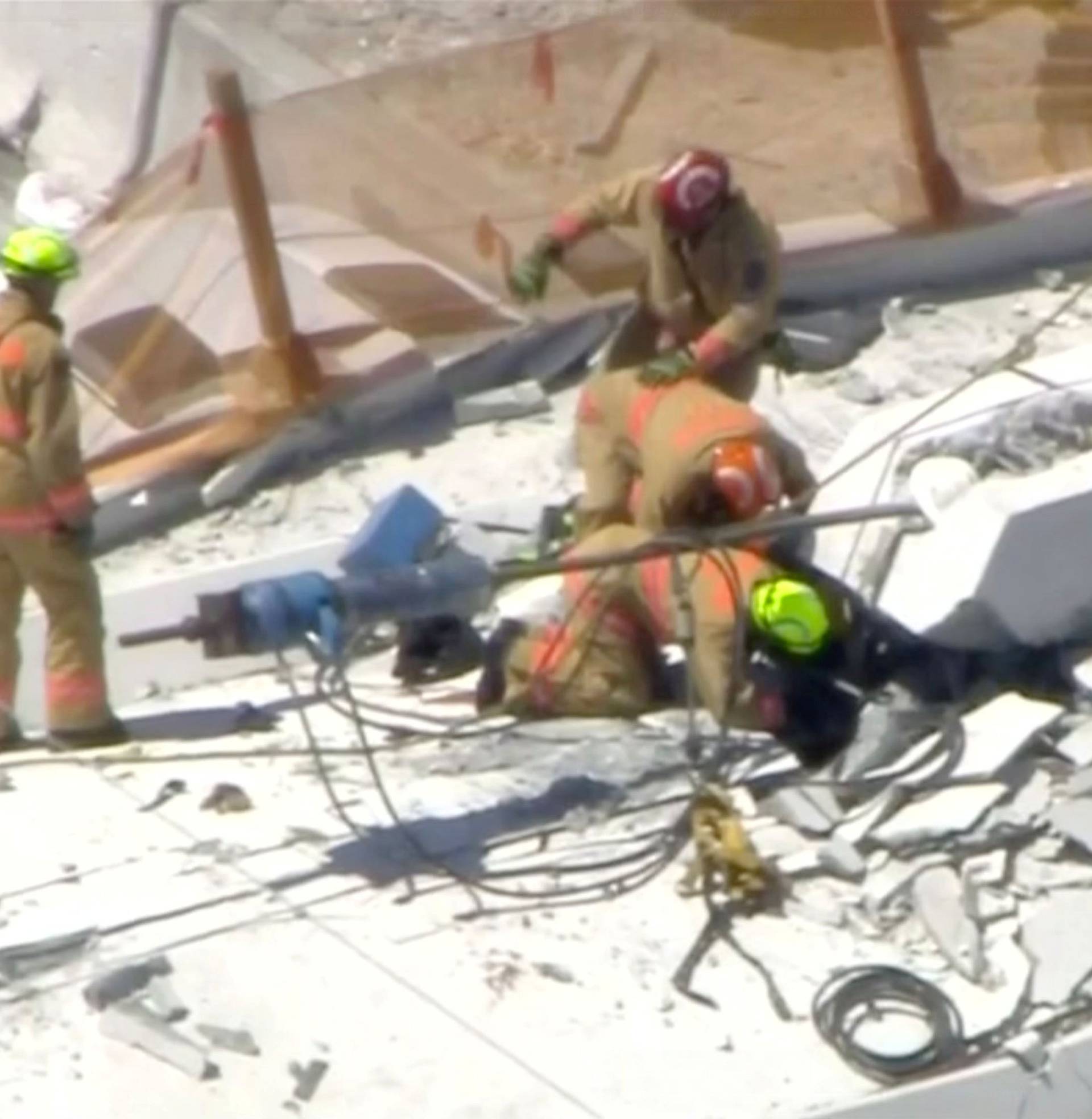 Emergency crews look for victims at the scene of a collapsed pedestrian bridge at Florida International University in Miami, Florida