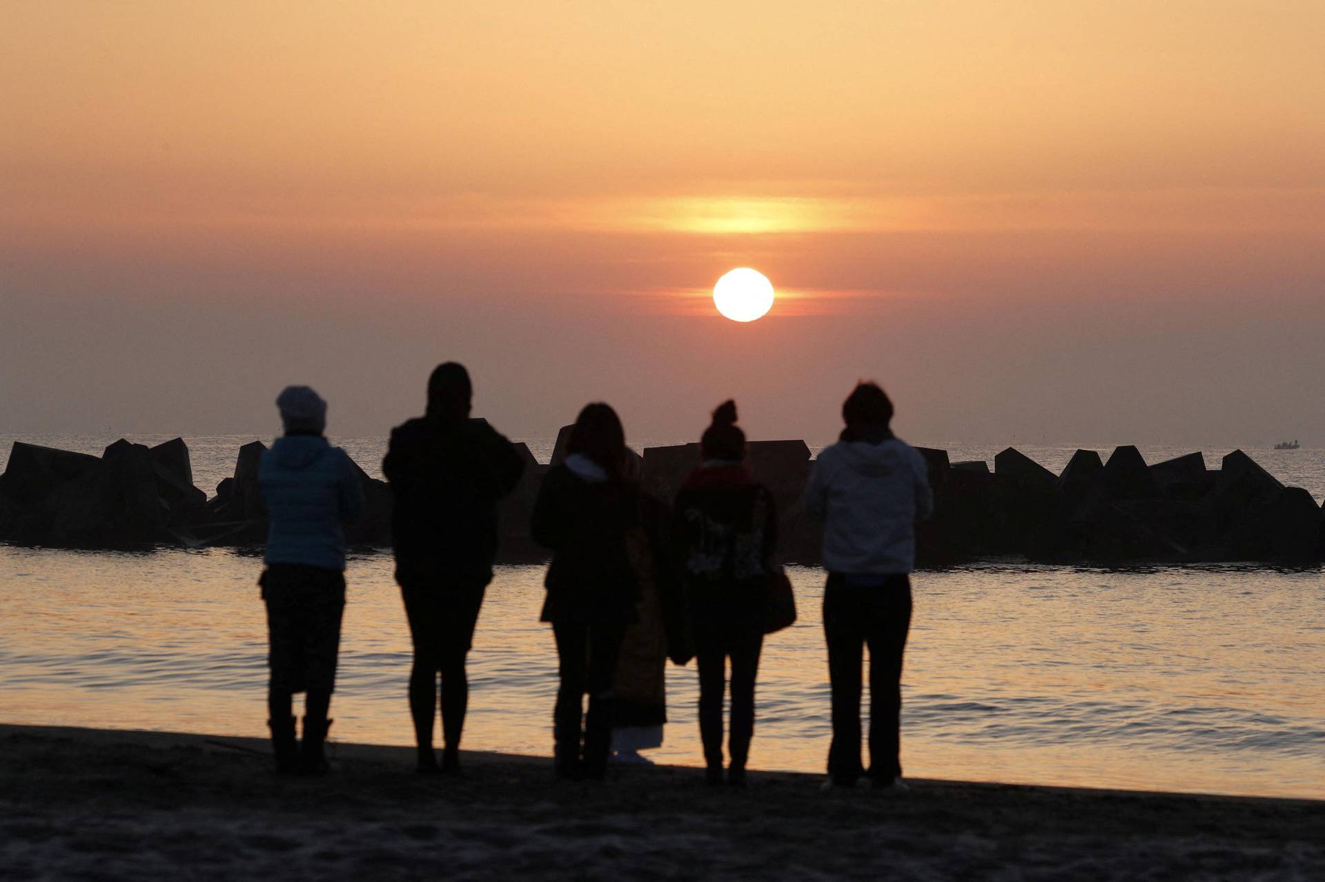 People pray on a beach in the Arahama district of Sendai