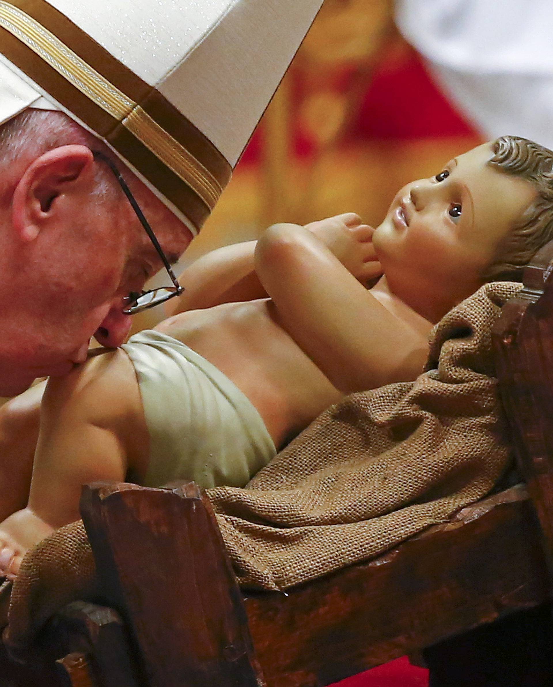 Pope Francis kisses a statue of baby Jesus at the end of the Christmas night Mass in Saint Peter's Basilica at the Vatican