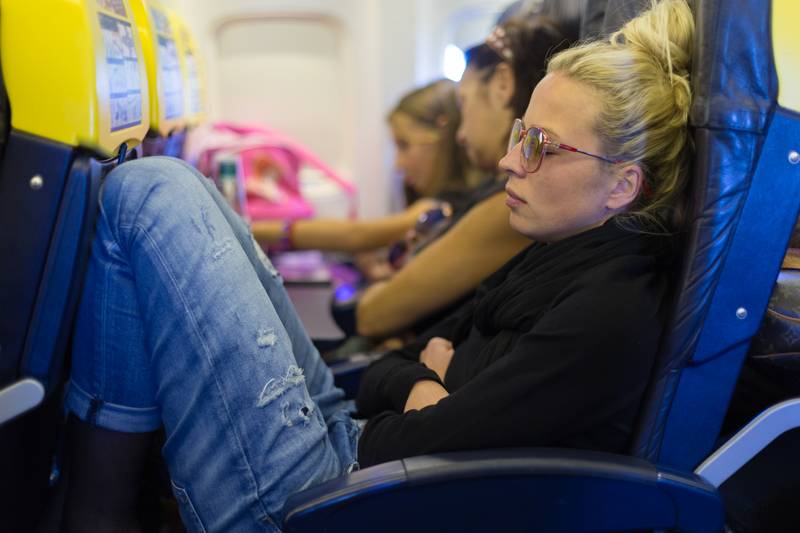 Tired lady napping on airplane.