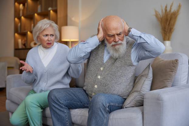 Elderly couple quarreling while sitting on sofa at home living room